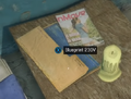 The blueprint's placement on the desk with the candle and magazines
